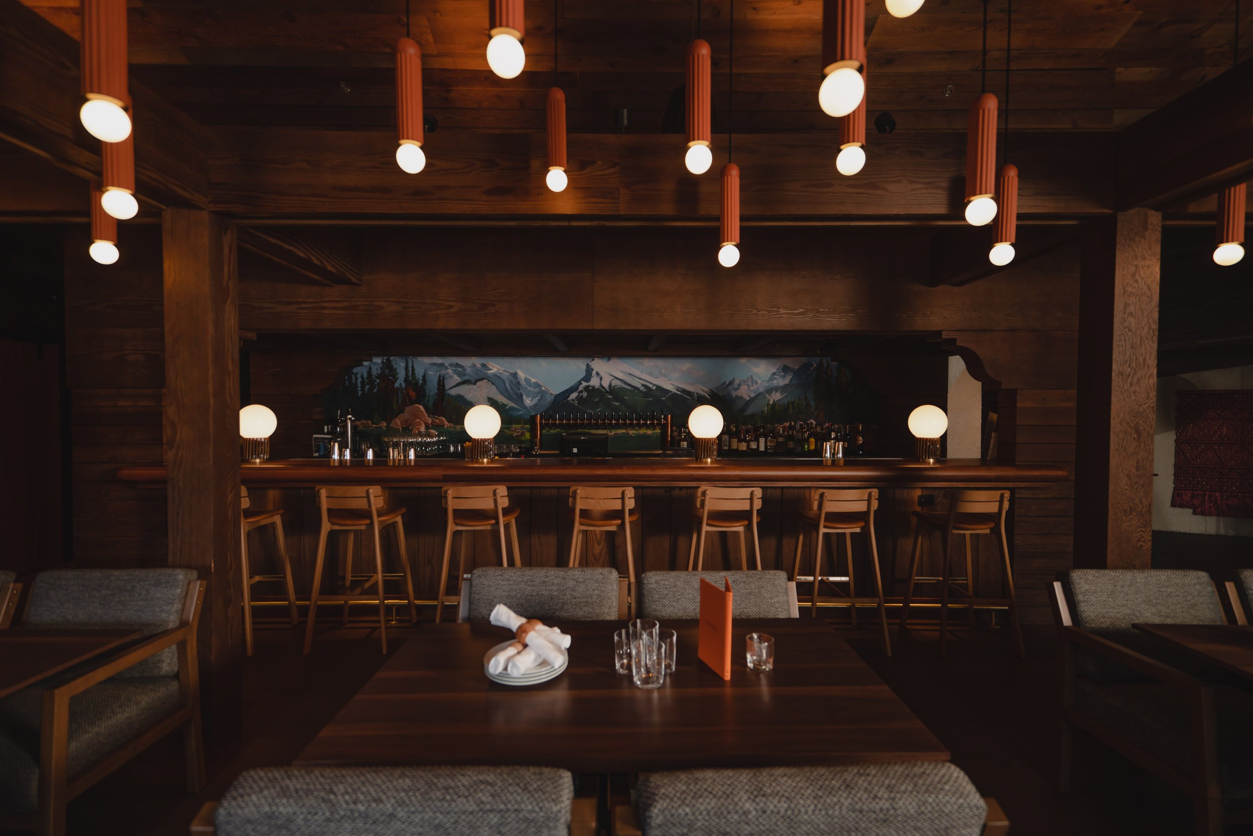 Bluebird’s upstairs bar with glowing pendant lights, timber walls and a mountain mural