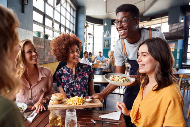 A server bringing dishes to a table of guests
