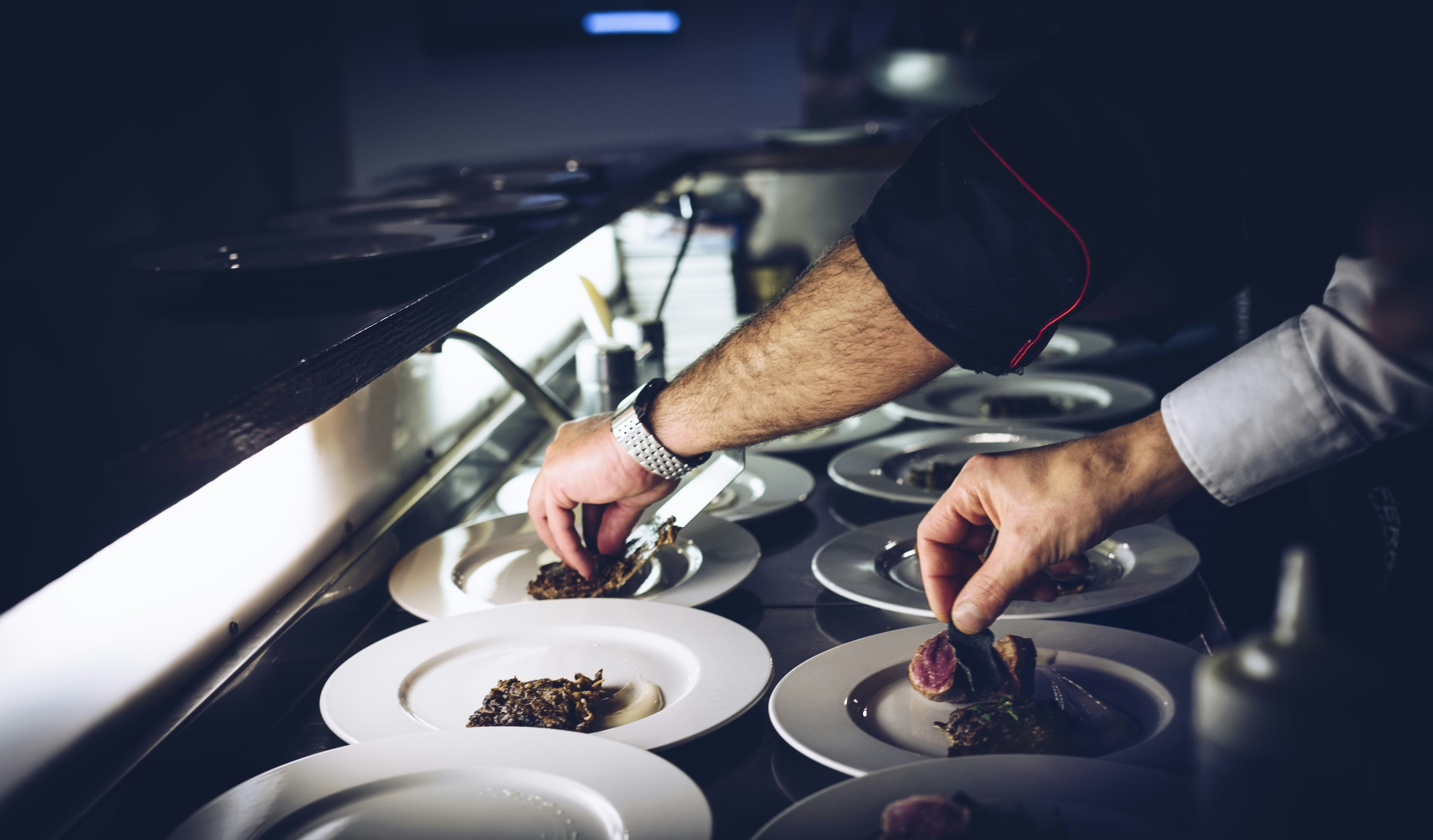 A chef plating dishes on the pass